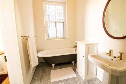 a bathroom with a bath tub and a sink at Charming Historical Cottage in Graaff-Reinet