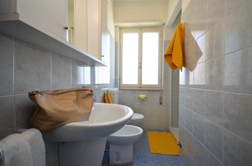 a white bathroom with a sink and a toilet at Appartamenti Gaby in Lignano Sabbiadoro