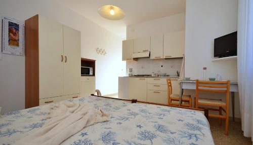 a bedroom with a bed and a kitchen with a table at Appartamenti Gaby in Lignano Sabbiadoro