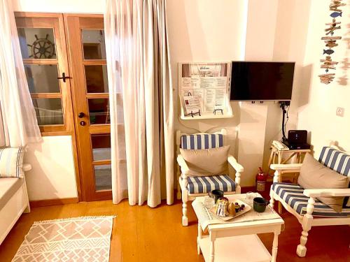 a living room with two chairs and a tv at Coralina Cottage in Koríthion