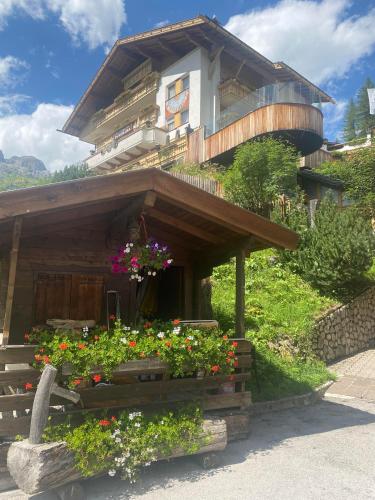 a building with a bunch of flowers in front of it at Dolomites Base Camp Hotel Olympia in Arabba