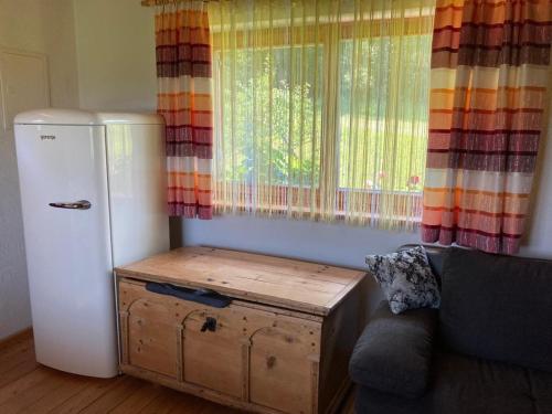 Zimmer mit einem Kühlschrank, einem Sofa und einem Fenster in der Unterkunft Gartenwohnung Hemma in Eberndorf