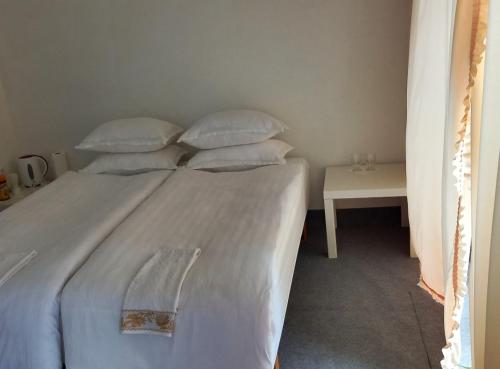 Bett mit weißer Bettwäsche und Kissen neben einem Tisch in der Unterkunft ApartamentFortuna1 in Palanga