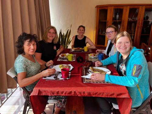 un grupo de personas sentadas en una mesa comiendo comida en Haika Home Lodge en Dar es Salaam