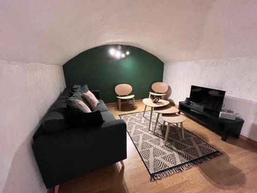 sala de estar con sofá negro y pared verde en L'Atypique T3 Stanislas Maisonnette avec cour en Orléans