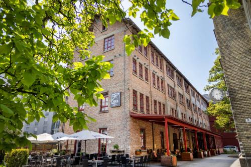 ein großes Backsteingebäude mit Tischen und Sonnenschirmen in der Unterkunft JUFA Hotel Bregenz in Bregenz