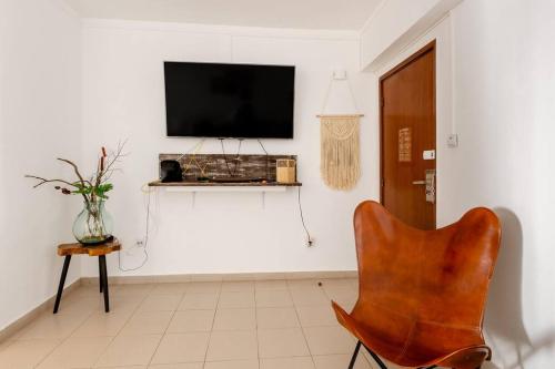 a living room with a chair and a television on a wall at Anna's Apartment Praia da Rocha in Portimão