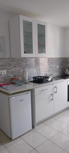 a kitchen with white cabinets and a counter top at Apartman Bloom in Osijek