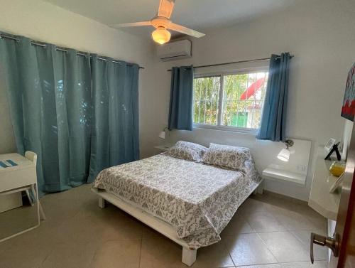 a bedroom with a bed and a window with blue curtains at JARDIN SECRET B1 in Las Terrenas