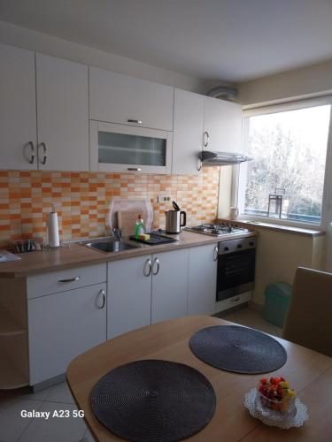 a kitchen with white cabinets and a wooden table at Apartman Bloom in Osijek