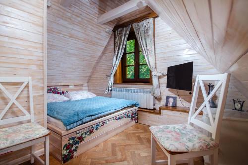 a bedroom with a bed with a tv and two chairs at Modrzewiowy Zdrój 