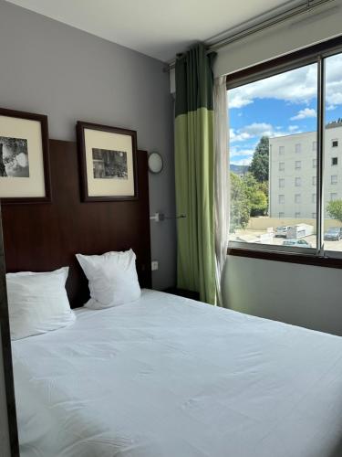 a bedroom with a large bed with a large window at Hôtel Du Centre Annemasse in Annemasse