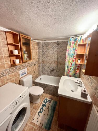 a bathroom with a toilet a sink and a washing machine at RITSA APARTMENT in Perea