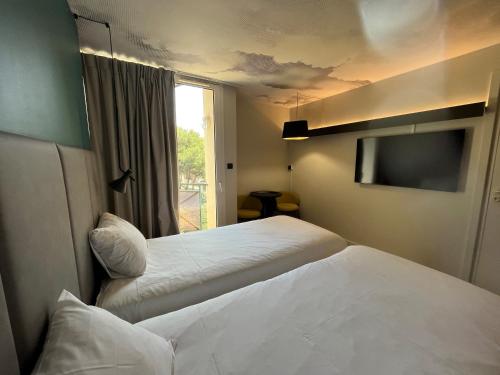 a hotel room with two beds and a television at ibis Sète Balaruc les Bains Bien-être et Spa in Balaruc-les-Bains
