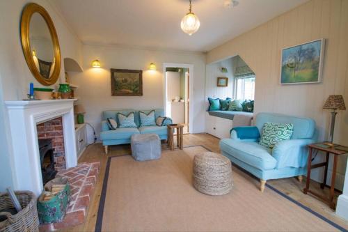 a living room with blue couches and a fireplace at Loke Cottage - Winchelsea Nr Rye in Winchelsea