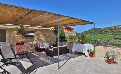 eine Terrasse mit einer Pergola, einem Tisch und Stühlen in der Unterkunft Il giardino degli aranci in Modolo