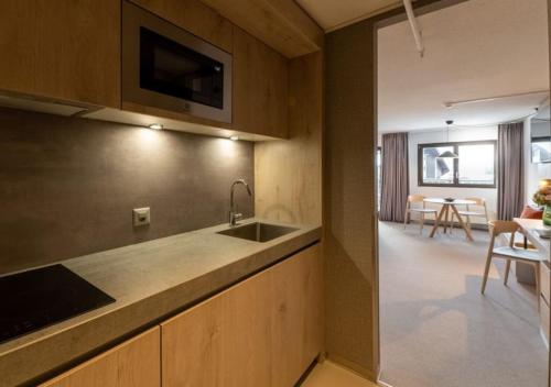 a kitchen with a sink and a table with chairs at Victoria Hotel & Residence in Villars-sur-Ollon