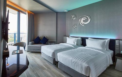 a hotel room with two beds and a couch at Grande Centre Point Pattaya in Pattaya