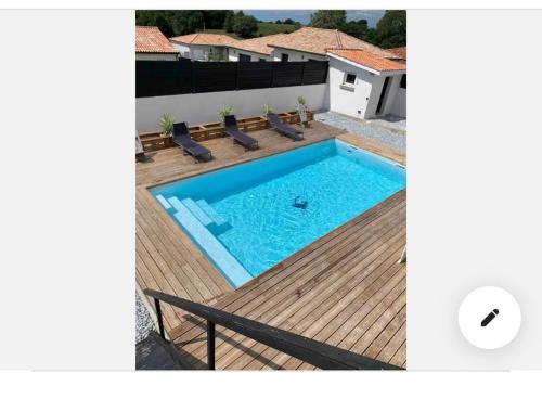 une piscine avec des chaises et une terrasse en bois dans l'établissement Maison au calme avec piscine, à Rivière-Saas-et-Gourby