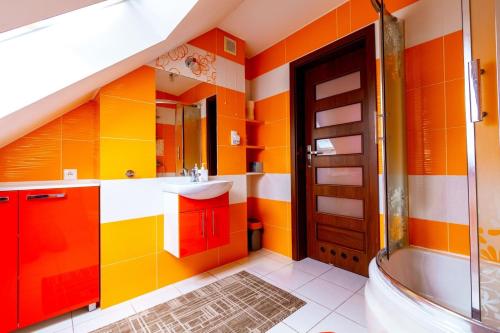 ein Badezimmer mit orangefarbenen und gelben Wänden und einem Waschbecken in der Unterkunft Jagodowy Domek in Święta Katarzyna