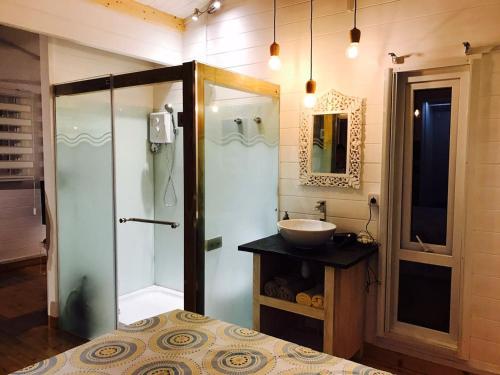 a bathroom with a glass shower and a sink at Between2Waters Chalet rental car offered in Tamarin