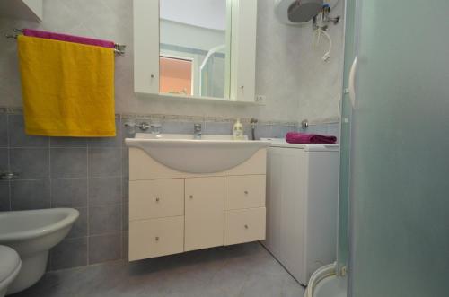 La salle de bains est pourvue d'un lavabo, d'un miroir et de toilettes. dans l'établissement Residenza Olimpo, à Lignano Sabbiadoro