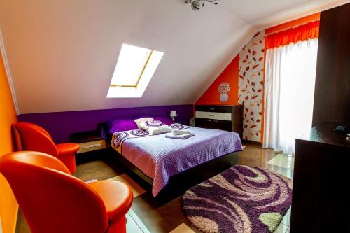 ein Schlafzimmer mit einem lila Bett und orangefarbenen Stühlen in der Unterkunft Jagodowy Domek in Święta Katarzyna
