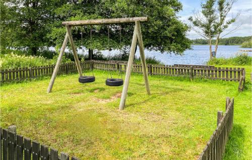 a swing set in a yard next to a fence at Lovely Home In Örkelljunga With Kitchen in Orkelljunga