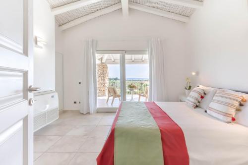 a white bedroom with a bed with a view of the ocean at Villa Mandorlo a soli 500 mt dal mare con piscina privata e vista mare in Costa Rei