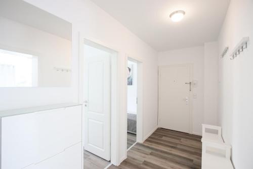 einen weißen Flur mit einer weißen Tür und einem weißen Stuhl in der Unterkunft Modernes und zentrales 4 Zimmer Apartment in Hamburg