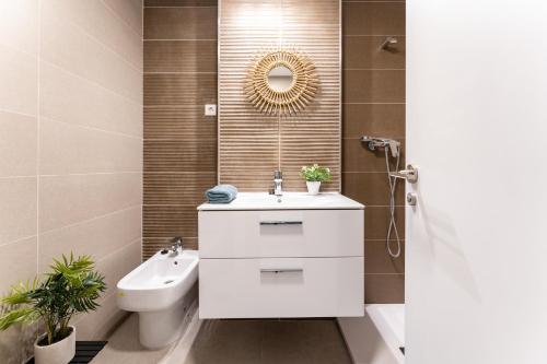 W łazience znajduje się umywalka, toaleta i lustro. w obiekcie MalagaSuite Duplex con Parking w Maladze