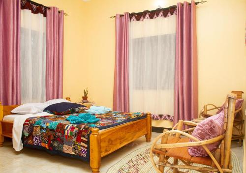 a bedroom with a bed and a chair and curtains at Home Feeling Kilimanjaro in Moshi