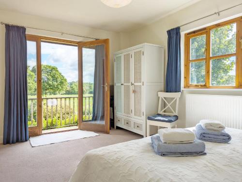 The Cottage at Hale Hill Farm, Pulborough في بولبورو: غرفة نوم بسرير ونافذة كبيرة