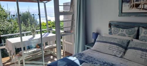 a bedroom with a bed and a balcony with a view at Amazing Grace B&B in Gansbaai