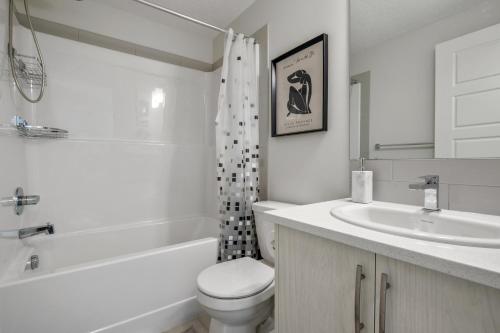 La salle de bains blanche est pourvue de toilettes et d'un lavabo. dans l'établissement Cozy Rockland Park Unit+Parking, à Calgary