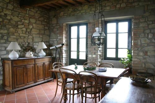 een eetkamer met een tafel en stoelen en een stenen muur bij Maridiana Alpaca Country House in Umbertide