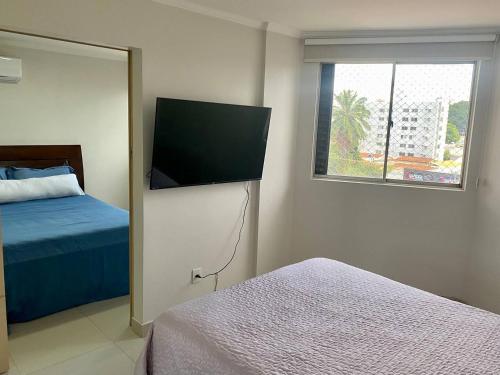 a bedroom with a bed and a flat screen tv at Apartamento perfeito, bem localizado, confortável, espaçoso e com bom preço insta thiagojacomo in Goiânia