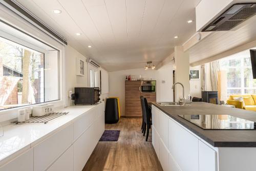 a kitchen with white cabinets and a large window at Chalet in Ursel in Aalter