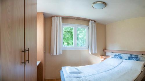 a bedroom with a bed and a window at Tíztó Vendégház in Baja