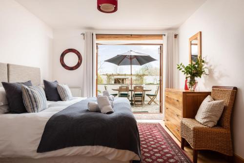 a bedroom with two beds and a table with an umbrella at East Trenean Farm Cottages -4 Luxury Cornish Cottages sleeping 20 with hot tubs, private gardens, rural views and EV facilities in Looe
