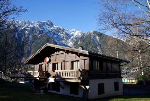 uma casa de madeira com uma montanha ao fundo em Appartement La Suite du Kandahar à Chamonix em Chamonix-Mont-Blanc