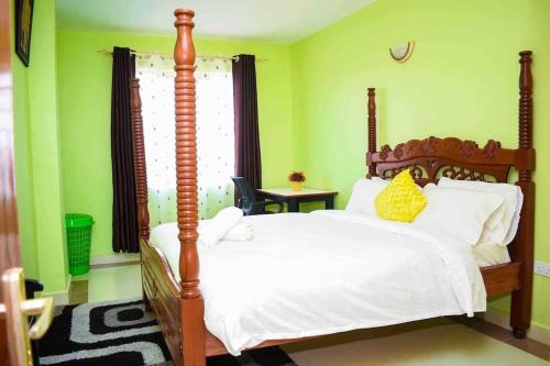 um quarto com uma cama de madeira com lençóis brancos e almofadas amarelas em Exquisite 1BR located in Garden Estate, Thome, Thika Rd, Nairobi em Nairobi