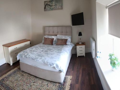 um quarto com uma cama branca e um tapete em THE LODGE (Belmullet town centre) em Belmullet