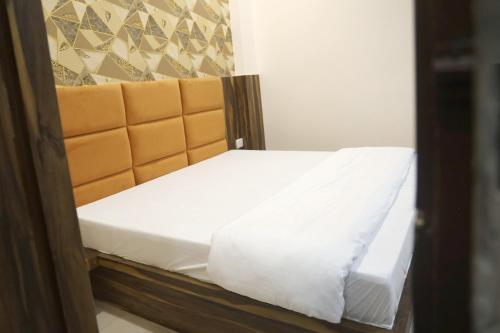 a small bed with white sheets and an orange headboard at Hotel Keshavam inn in Mathura