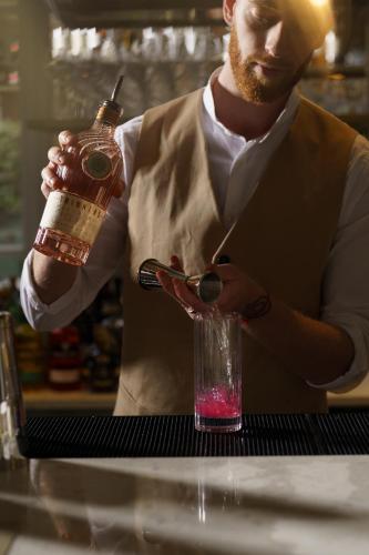 a man is holding a drink in a glass at Elkonin Tel Aviv - MGallery Hotel Collection in Tel Aviv