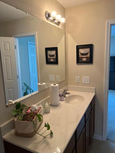 a bathroom with a sink and a large mirror at Stylish, Cozy Corporate Townhome with Pool! in Greensboro