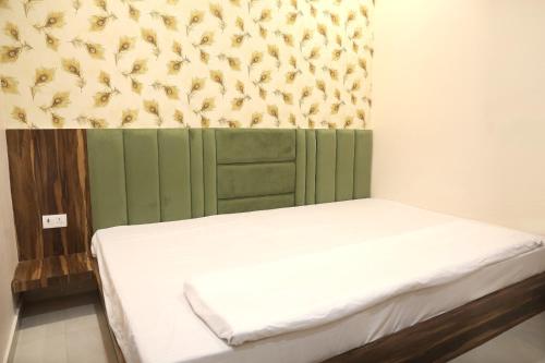 a bedroom with a bed with a green headboard at Hotel Keshavam inn in Mathura