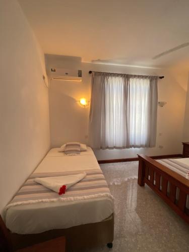 a small bedroom with two beds and a window at Didi's Dream apartments in Anse Kerlan
