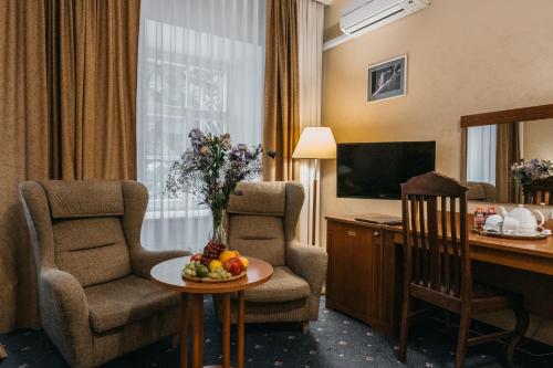 a hotel room with a desk and chairs and a table with fruit at Hotel Rinno in Vilnius