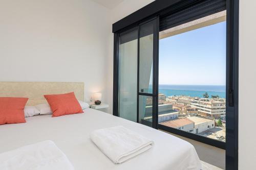 una camera con un letto bianco e una grande finestra di WintowinRentals New and Sea View a Torre de Benagalbón